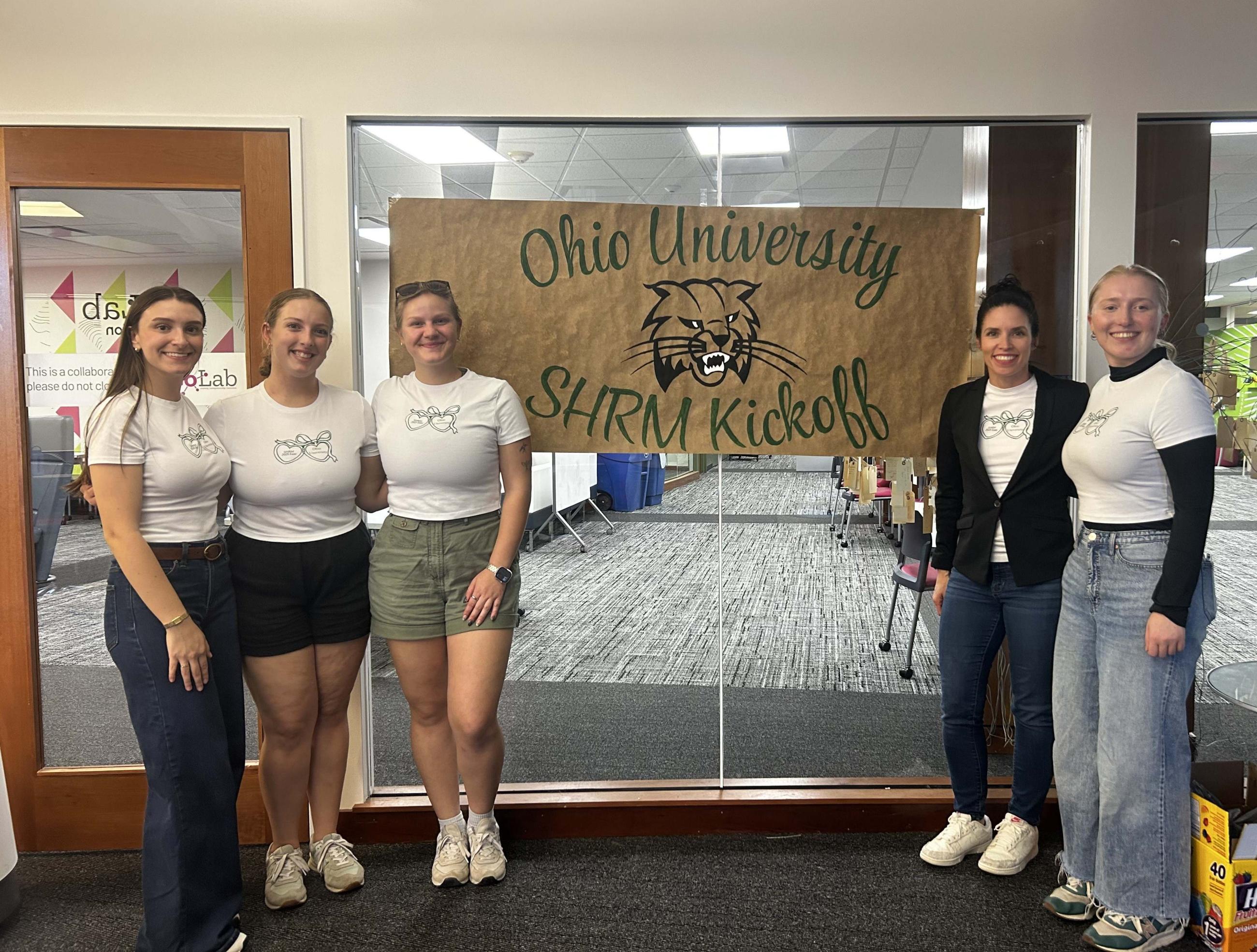 shrm students standing beside a sign