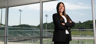 An Ohio University sports administration student poses in front of a football stadium