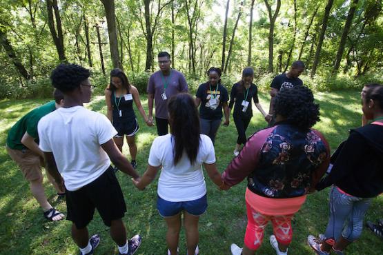 Business students hold hands while doing team-building games in an outdoor setting