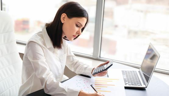 Woman working on computer and taking notes