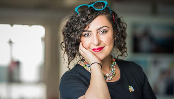 Female MBA student smiling at camera while wearing colorful accessories