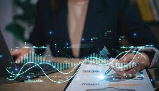 Business analyst at a desk with an overlay of charts and graphs floating above desk