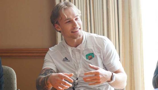 MSM graduate, Keegan Wilburn, sitting at conference table speaking to fellow students