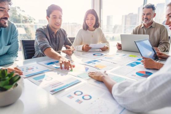 Master of business analytics students at table reviewing graphs and charts together