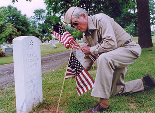 Alvin Baird at WWII cemetery with flag, in uniform