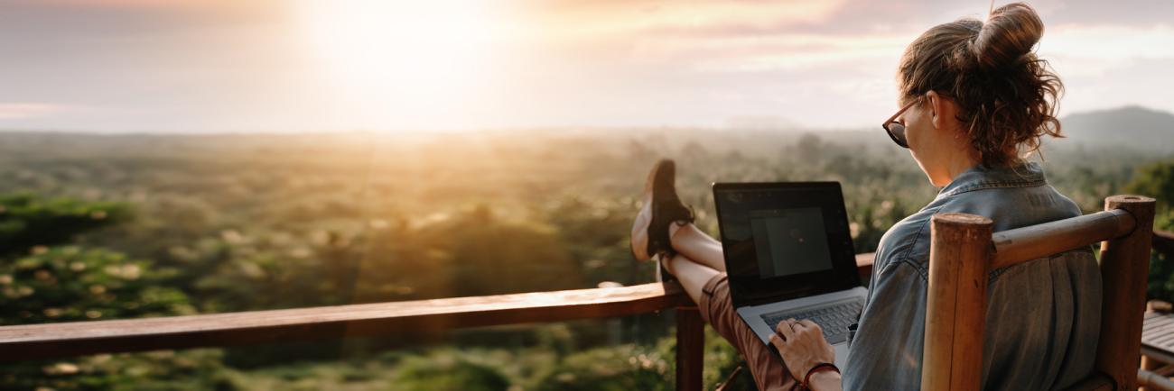 woman on laptop overlooking wooded hills