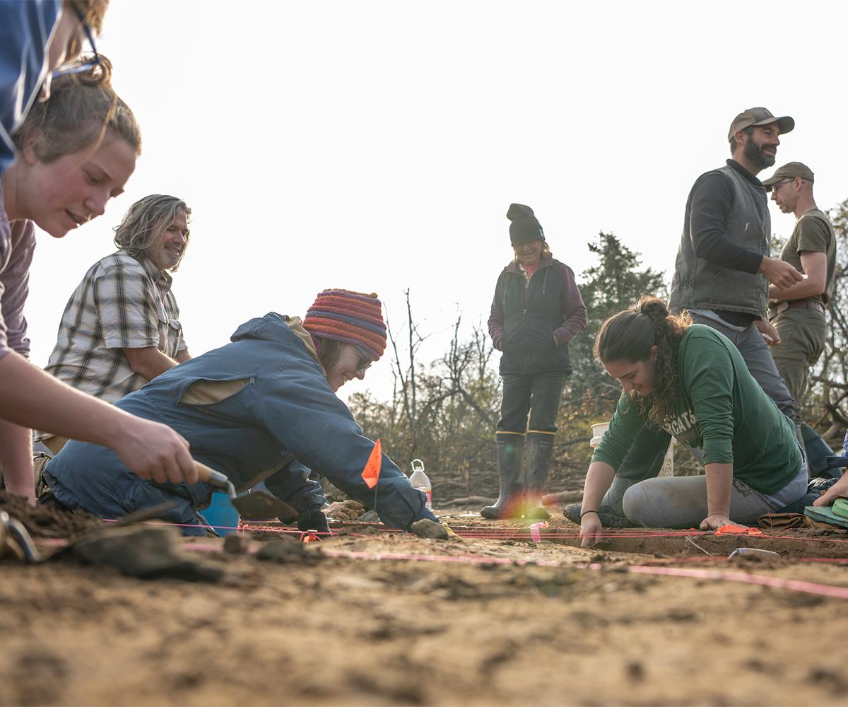 Students dig at an archaeological field site.