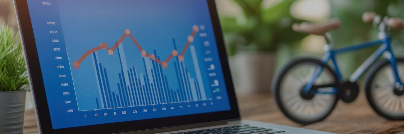 A big-tired bicycle next to an open laptop 