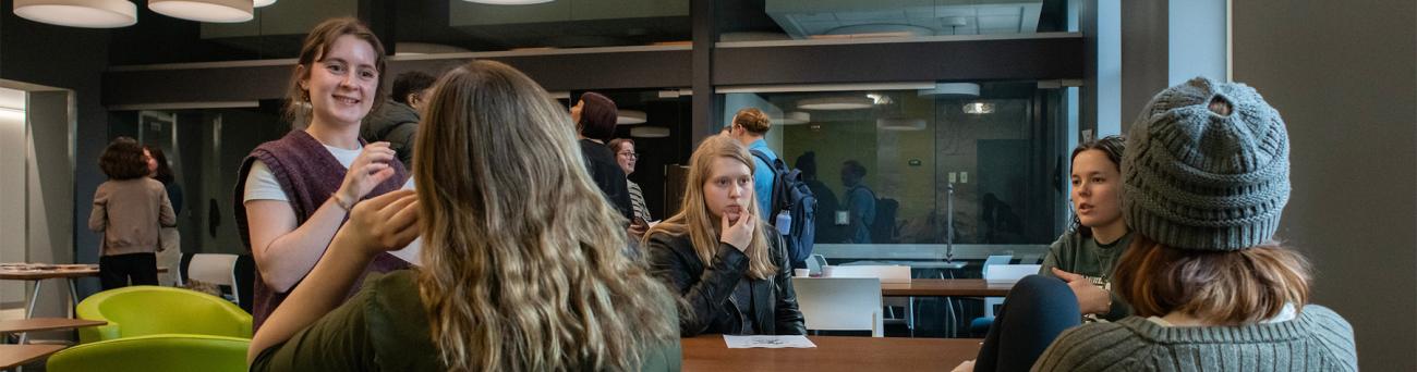 A group of students sits at a table and has a conversation together.