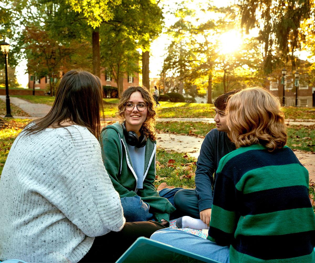 Students talk while sitting on College Green.