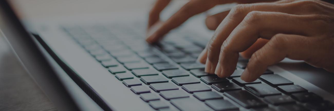 fingers typing and writing on a laptop keyboard