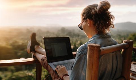 Woman sitting on a deck looking out over hills at sunset