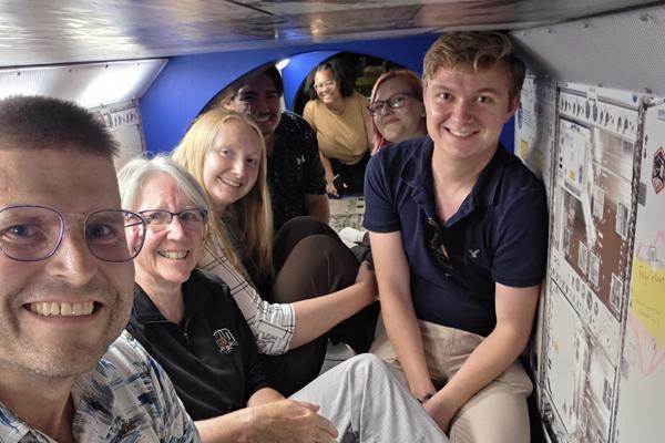 Faculty and students climb into a space vehicle at the Kennedy Space Center Museum.