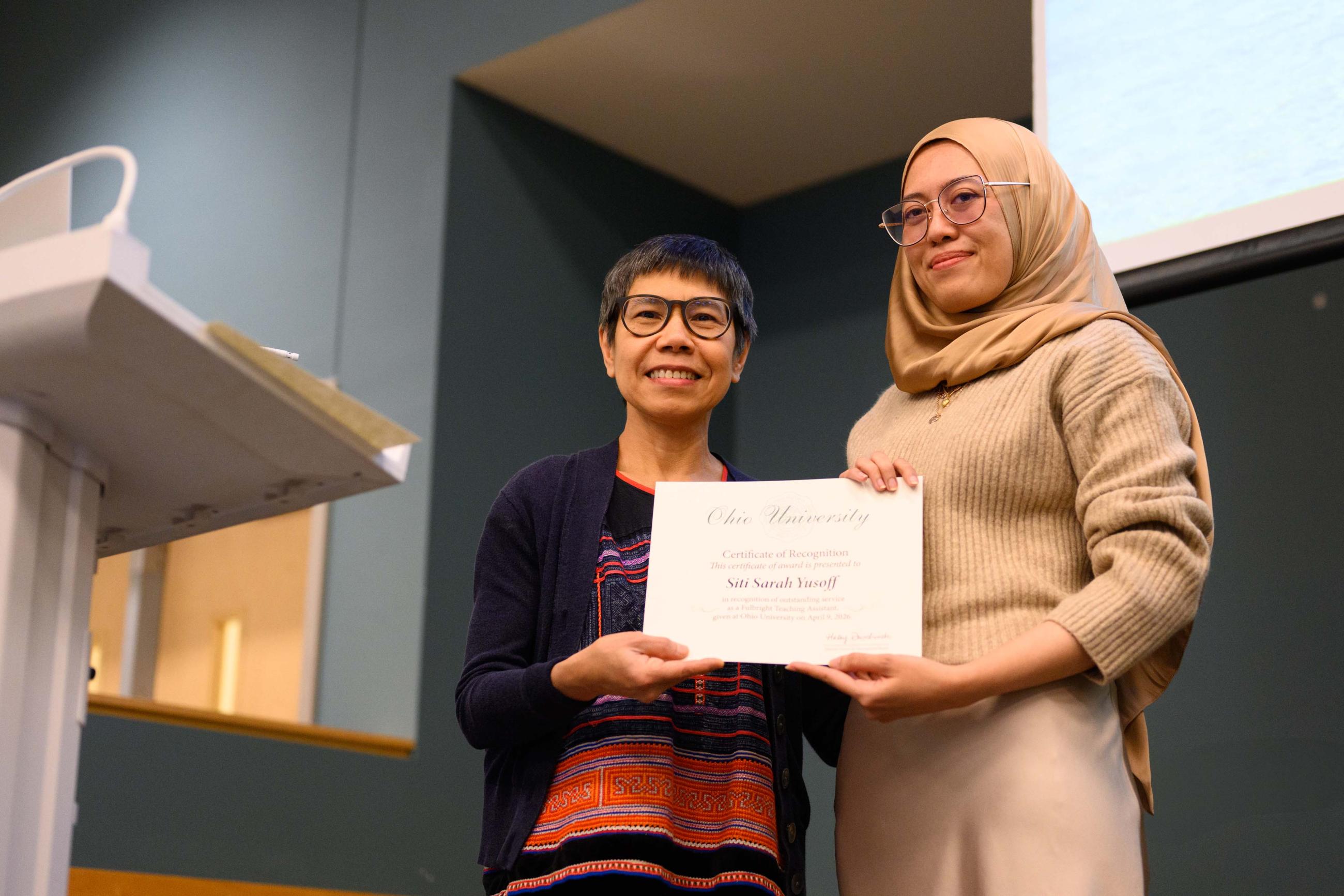 Professor Pittaya Paladroi-Shane presenting female student wearing a hijab a certificate.