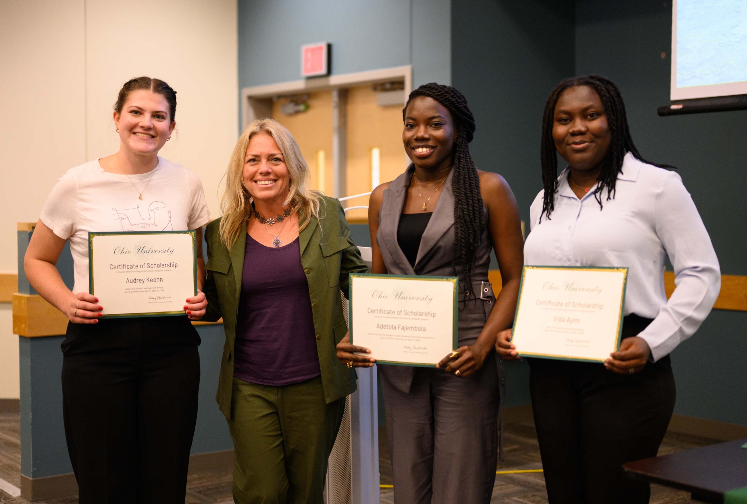 Dr. Haley Duschinski surrounded by three students proudly holding certificates.