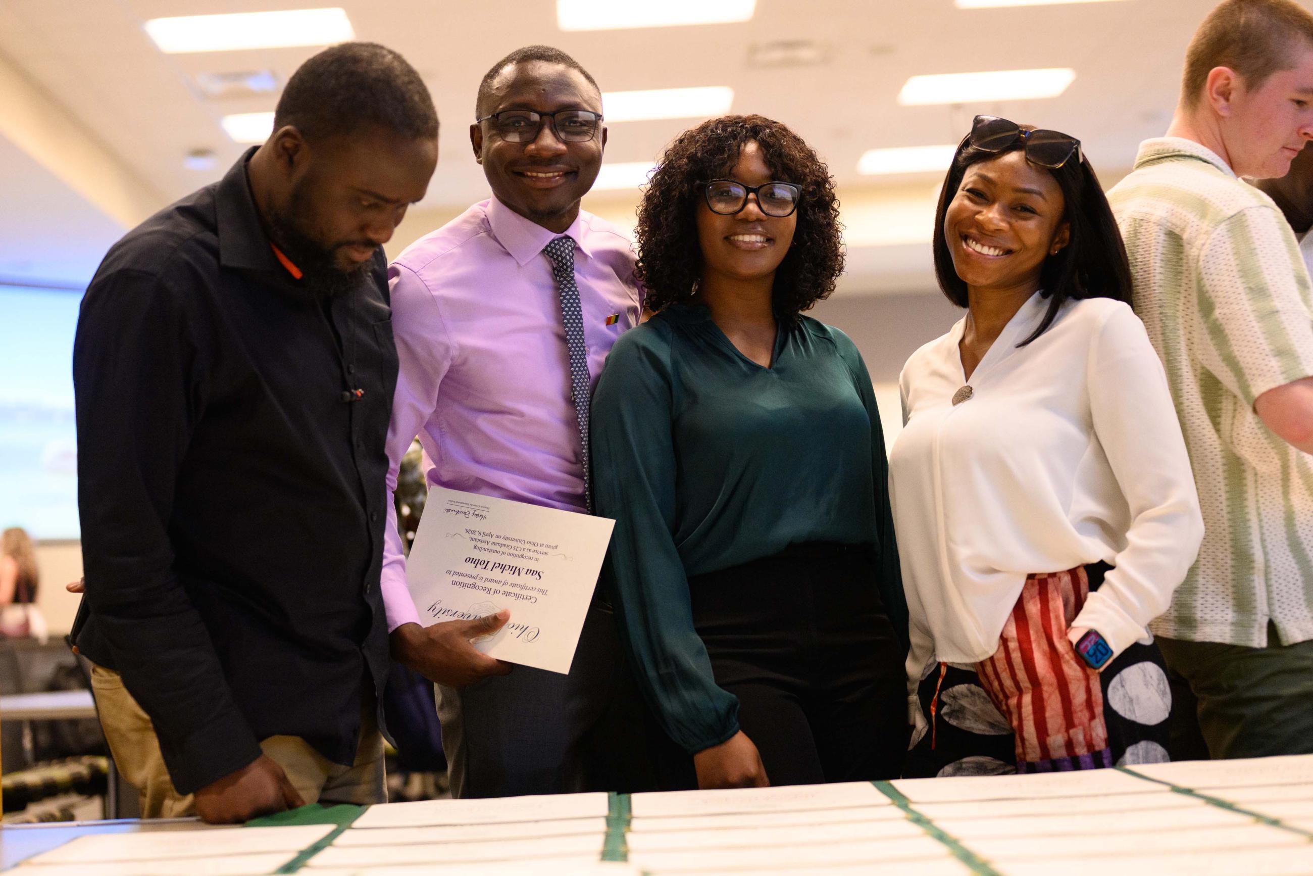 Four graduate students posing for a picture at the certificate table.