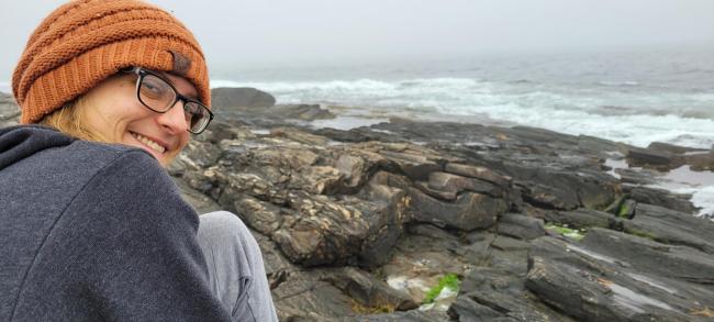 A photo of Jean Vandervaart standing on a rocky coastline.
