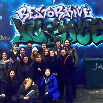 Spring break in Northern Ireland group photo in front of "Restorative Justice" graffiti