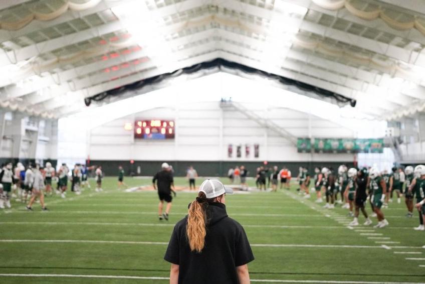 Woman standing on field inside an indoor football arena