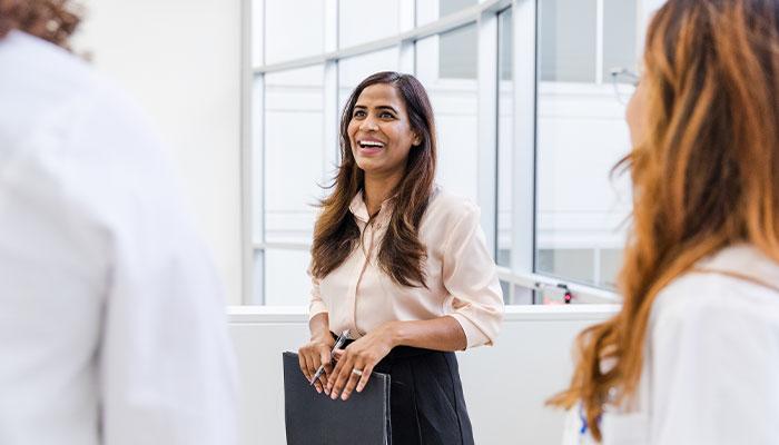Project manager holding portfolio while speaking to coworkers