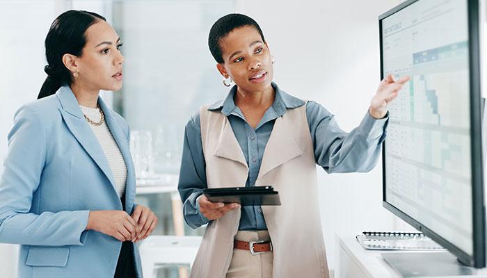 Two health policy analysts reviewing data on office monitor