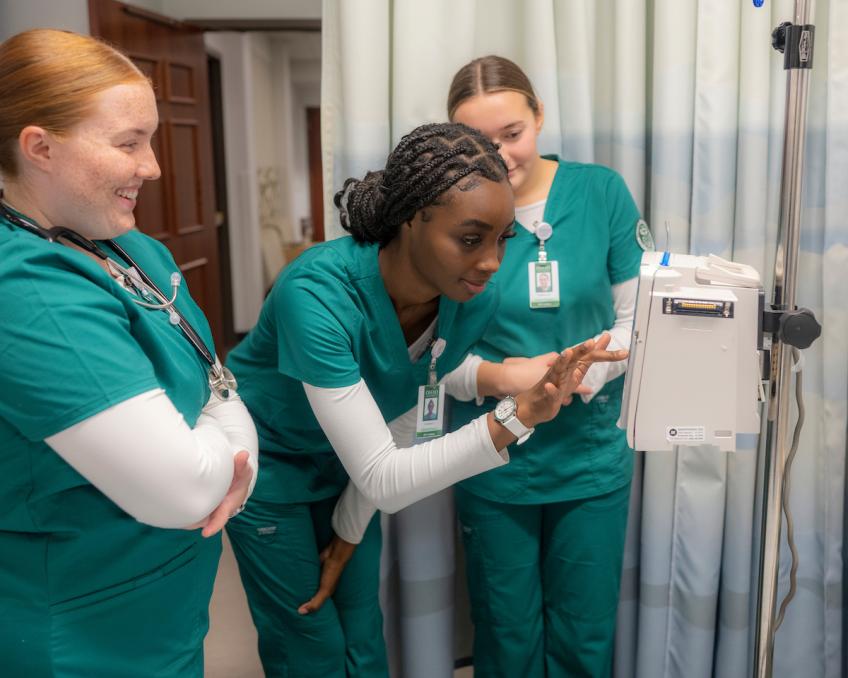 Three nursing students learn how to use medical equipment