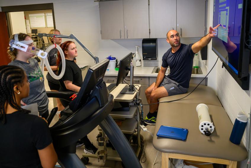 Exercise physiology students look at data from a lab participant's breathing test