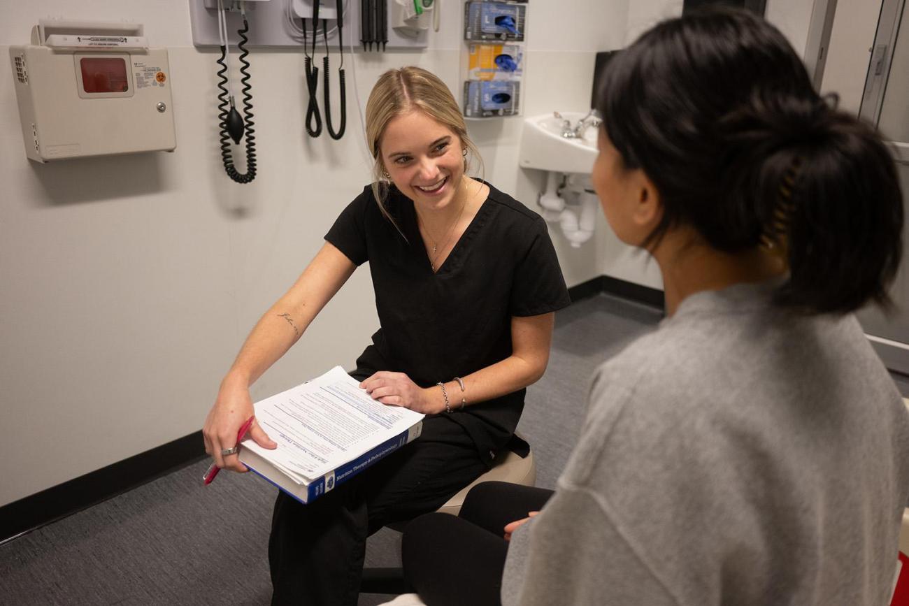 Nutrition Science student with a clipboard talking to a patient (or simulated patient)