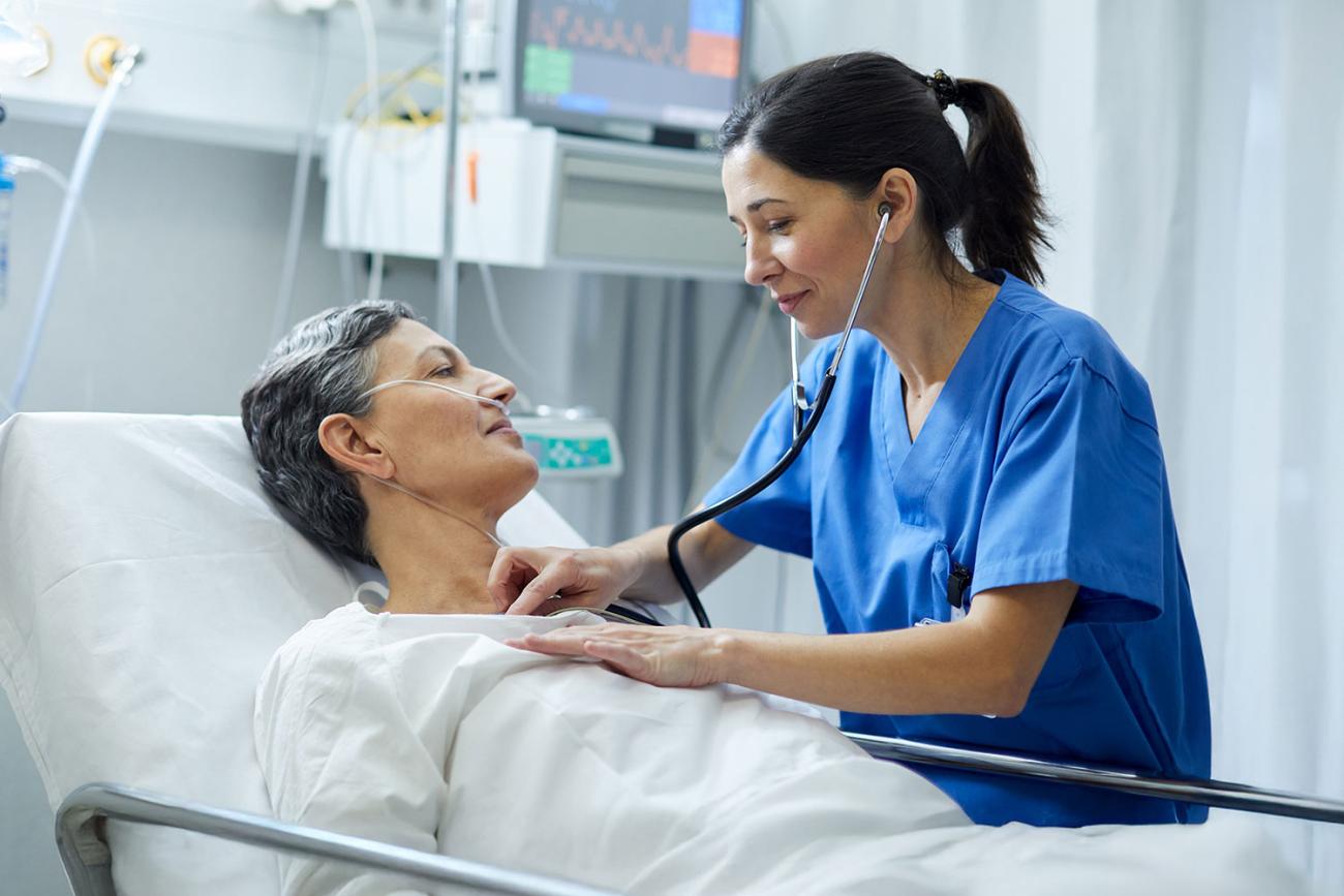 Female Nurse Practitioner wearing blue scrubs and stethoscope, holding a clipboard. Ohio University Emergency Nurse Practitioner Certificate program.