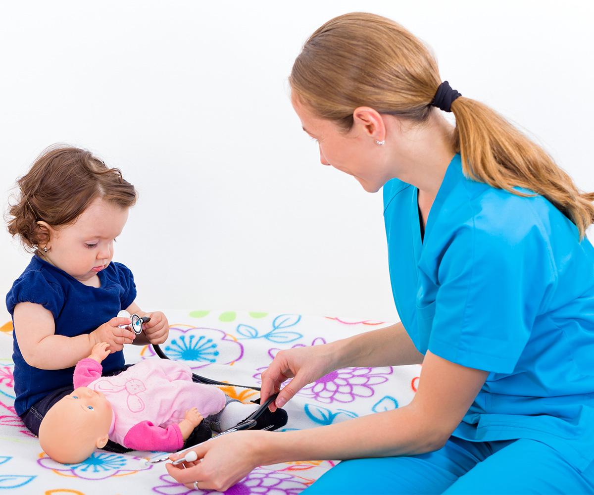 A clinician shows demonstrates a medical experience using a doll for a toddler.