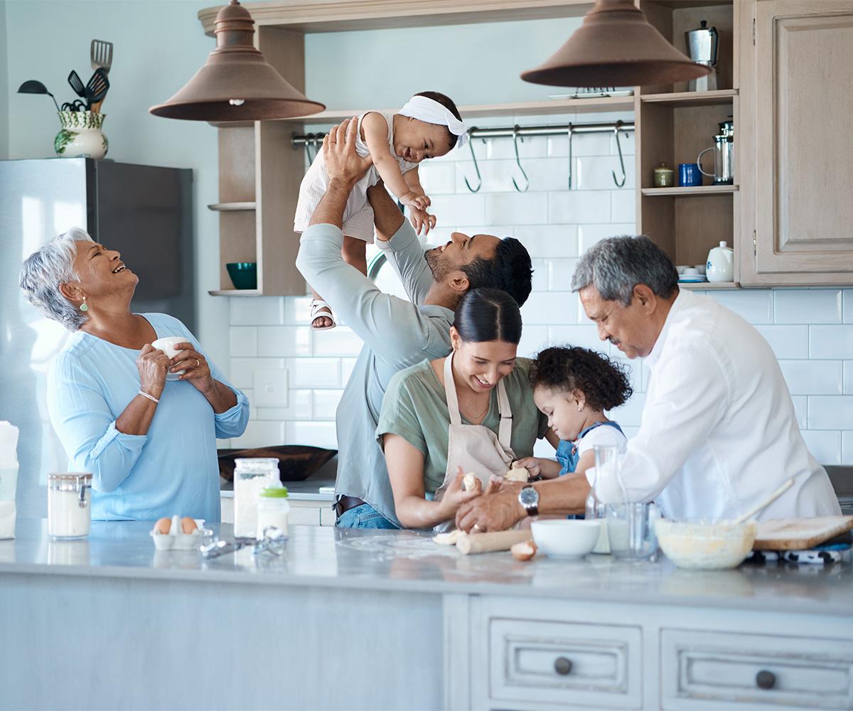 A family laughs and plays together in a kitchen.