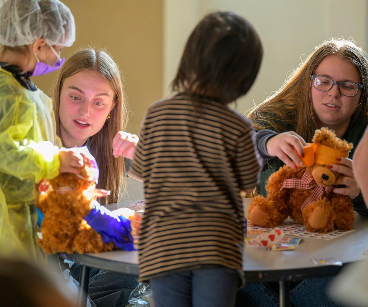 Two students work with children during a teddy bear clinic.
