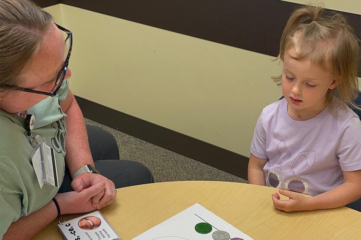 A Speech language pathology graduate students does an activity with a child in the PALS program.