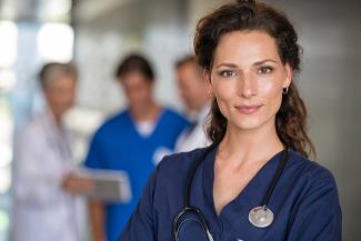 Brunette with curly hair wearing blue scrubs and a stethoscope