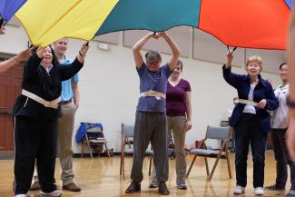 group of adults play with a large parachute