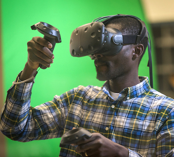 Student with virtual reality headset in front of a greenscreen.