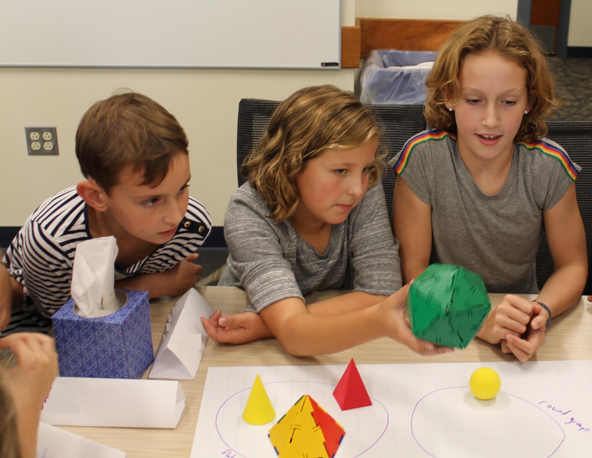 Three children working with math materials