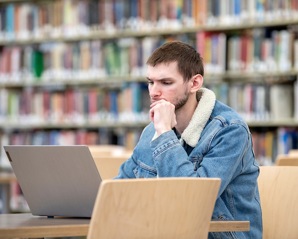 Student Sitting in the library looking at a laptop