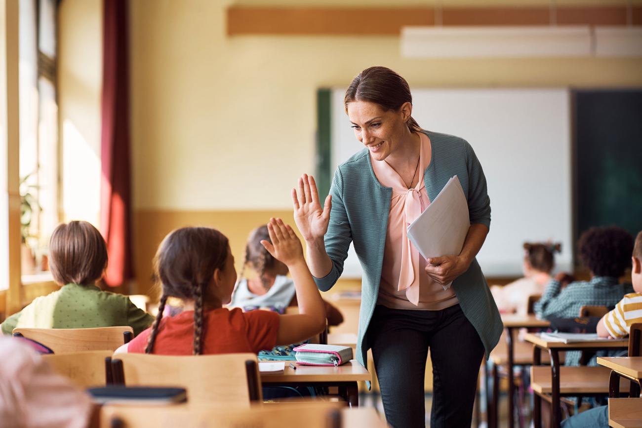 Teacher high-fives a student in an elementary classroom