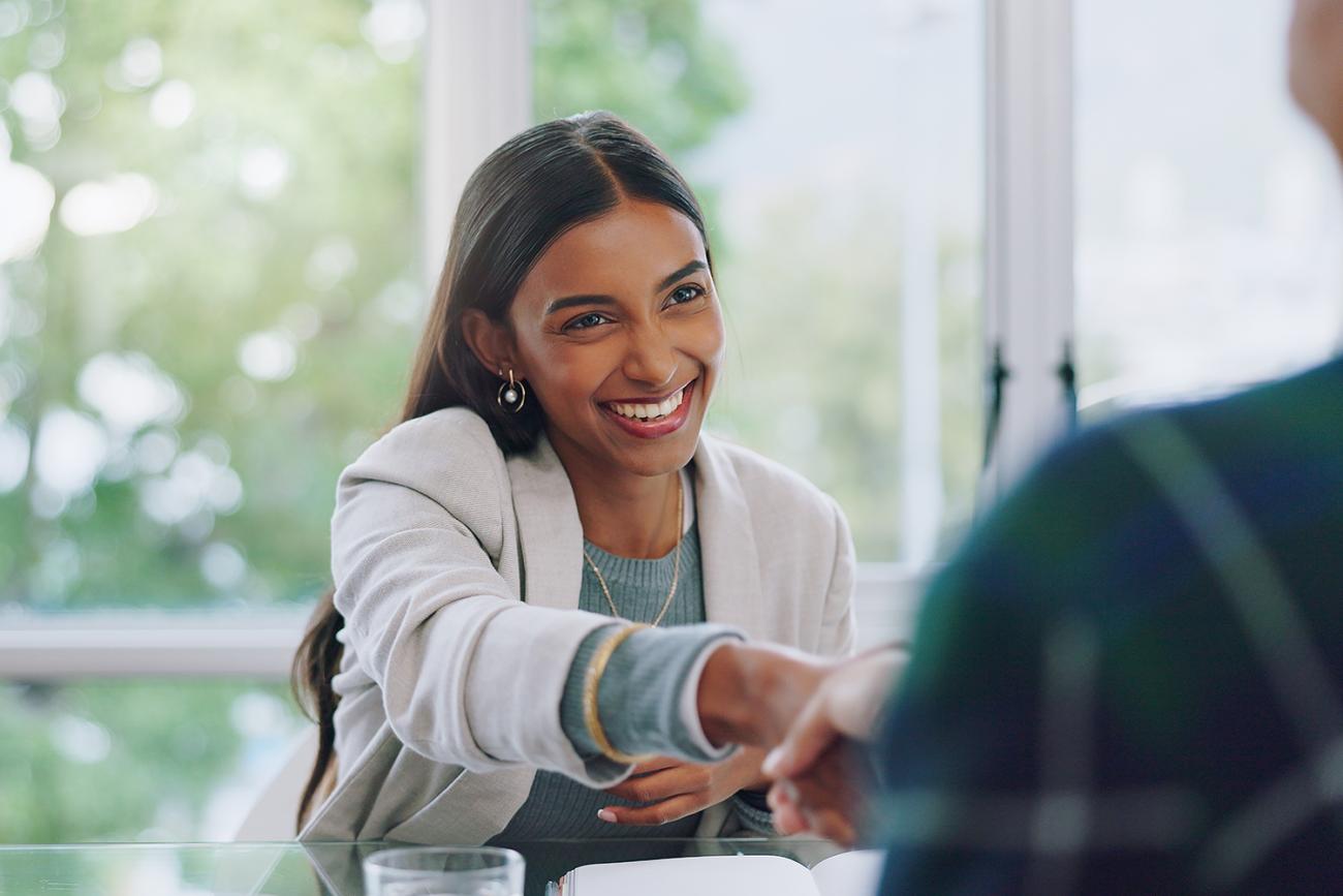 Woman in business attire shaking hands with someone off screen