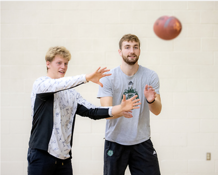 physical education students throwing a football in the gym