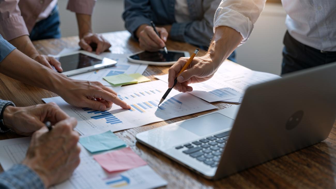 a group of professionals looking at graphs spread out over a conference table
