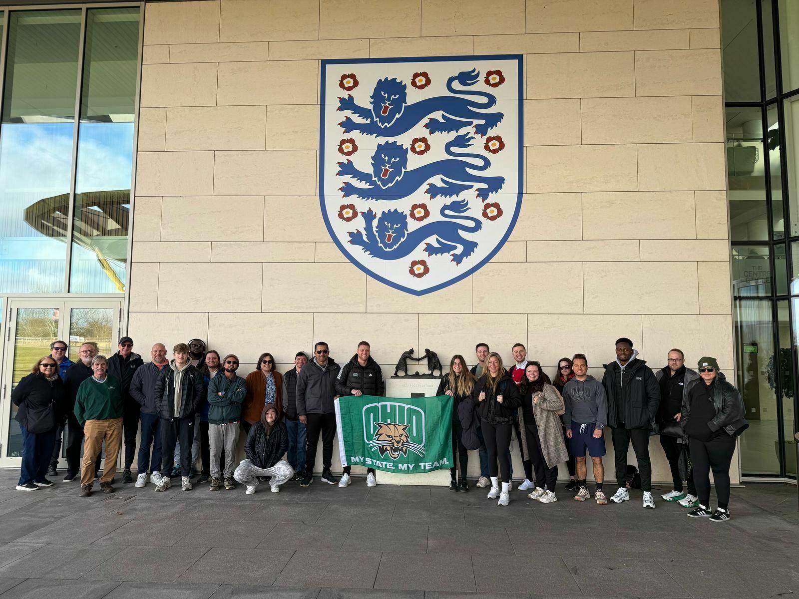 large group OHIO alumni holding a OHIO Bobcats flag in England