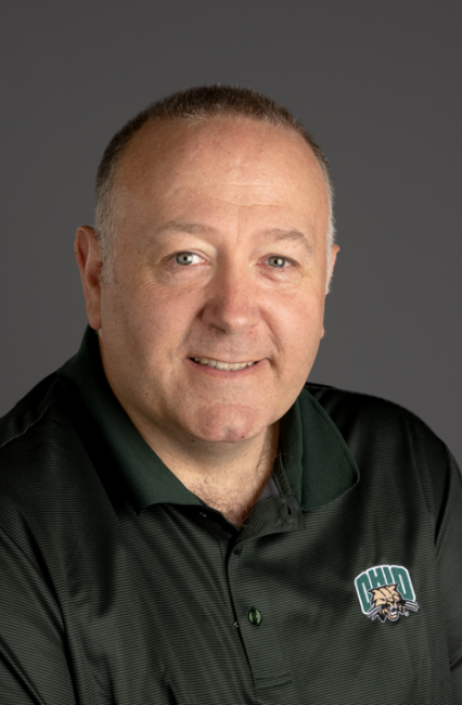 Headshot of a smiling Giles Lee wearing a green polo with the Ohio University Attack Cat logo 