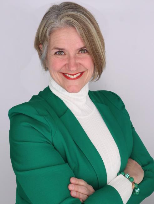 Headshot of a smiling Marcy Keifer Kennedy  in a green jacket and white turtleneck