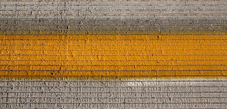 Orange stripe painted on a rough concrete-like material segmented into narrow strips