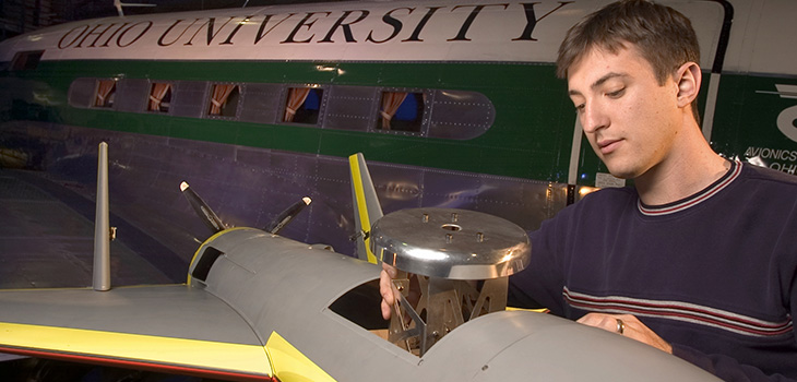 Student lifting a metal piece from the body of a small unmanned aerial vehicle