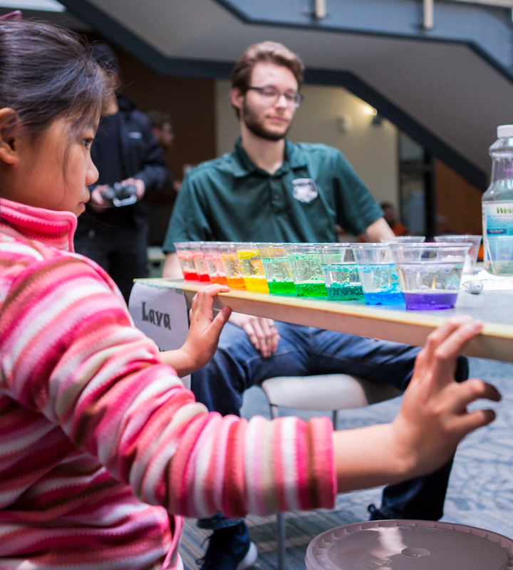 Kids observing multi-colored liquids in cups