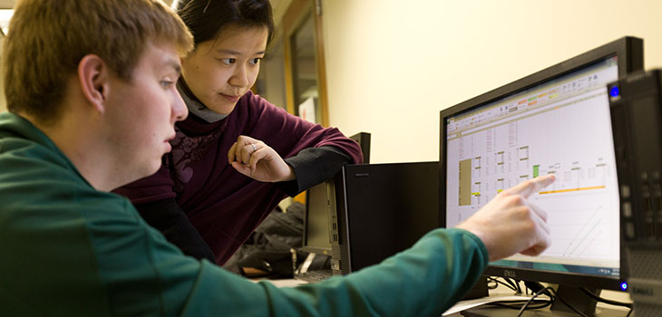 Two students look at a system map on a computer screen