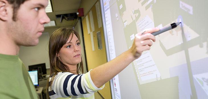 students writing on a smart board